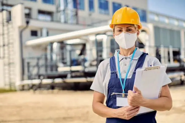 construction worker standing in front of job site with clipboard in hand